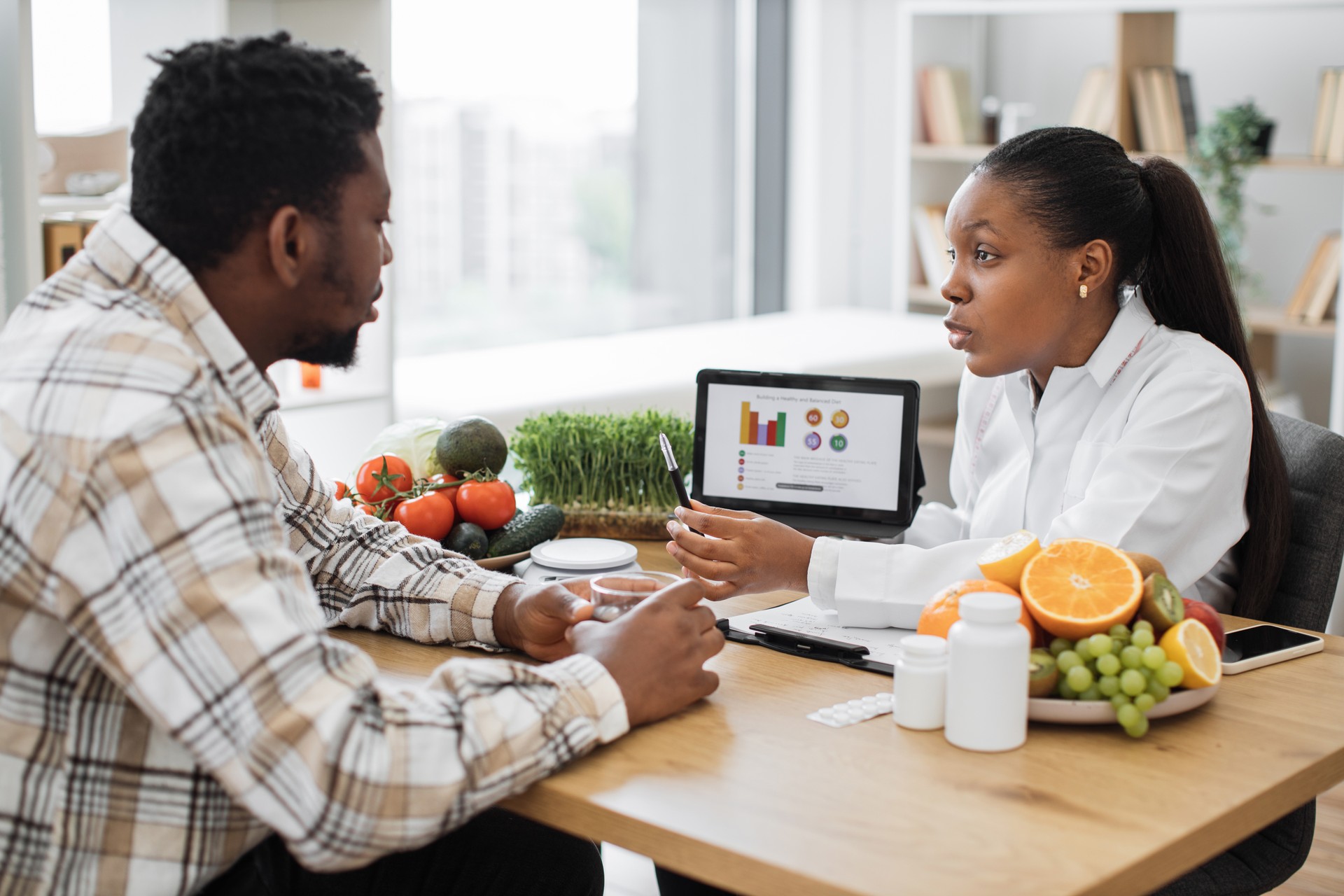 Expert in diet displaying client's data on tablet via graphs